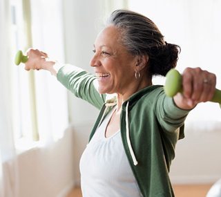 A smiling woman exercising with hand weights