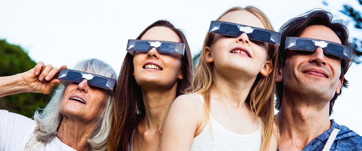 A family wearing dark glasses while looking to the sky