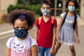 Children wearing masks outside a school that is reopening.