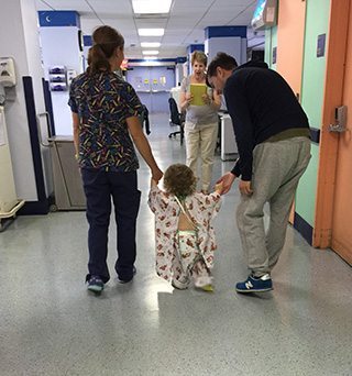 Darcy being helped during a walk down a hospital hallway