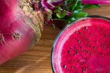 A glass of pink juice and a beetroot