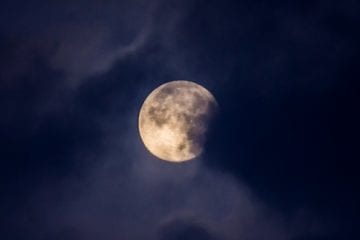 A moon partially hidden by clouds