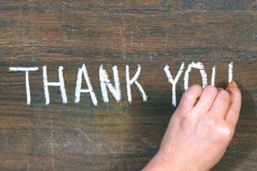 The words "thank you" written on a chalkboard