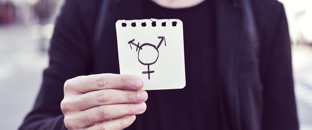 A person holding a piece of paper with a transgender sign on it