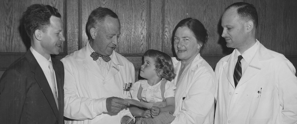 Portrait of Dr. Dorothy Andersen with a young patient and other healthcare providers