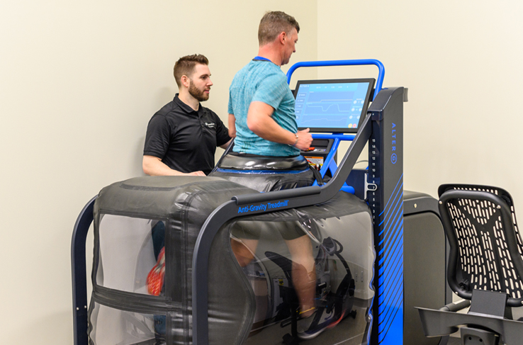 A man running on a treadmill while being watched by a healthcare provider