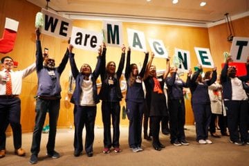 employees hold signs that spell we are magnet