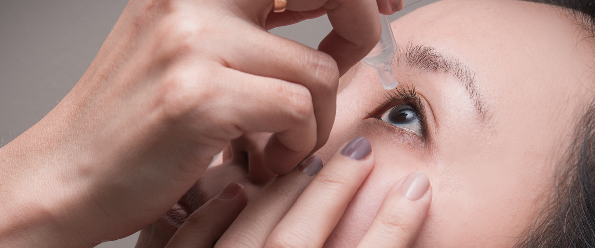Photo of woman adding eye drops to eye