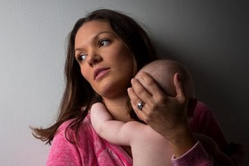 Distressed mother with signs of postpartum depression holding infant