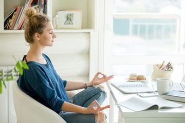 Woman sitting in a chair at a table doing yoga.