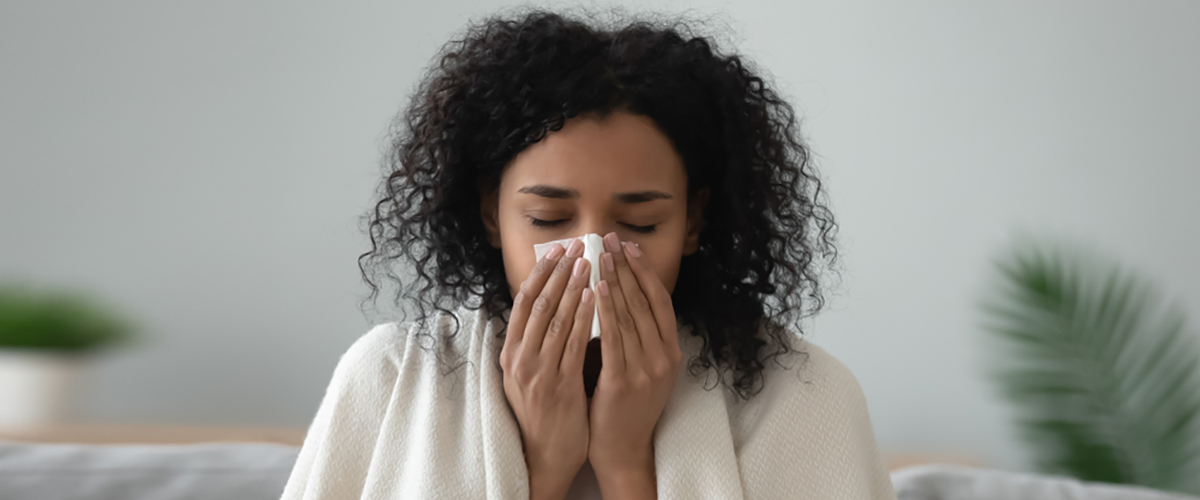woman blowing her nose from seasonal allergies