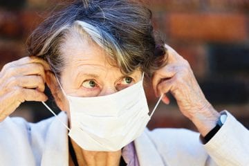 Senior woman removing a face mask.