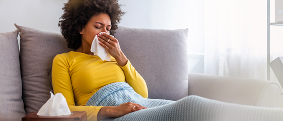 Woman on a couch with either the flu or COVID-19.