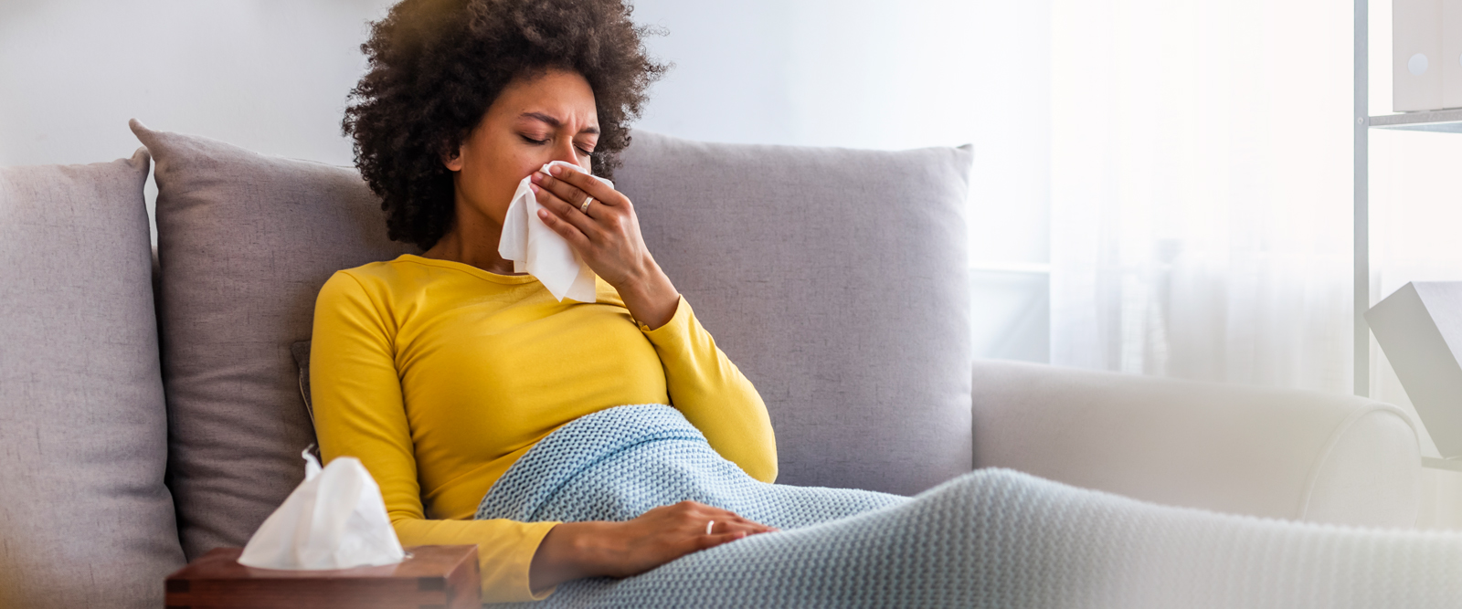 Woman on the couch sick with either flu or COVID-19.