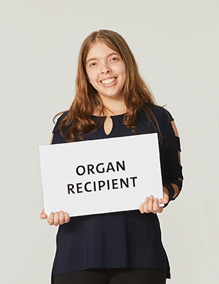 Organ recipient Kali Waters holding a sign that reads "organ recipient."