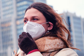 Woman wearing N95 mask and showing how to wear it.