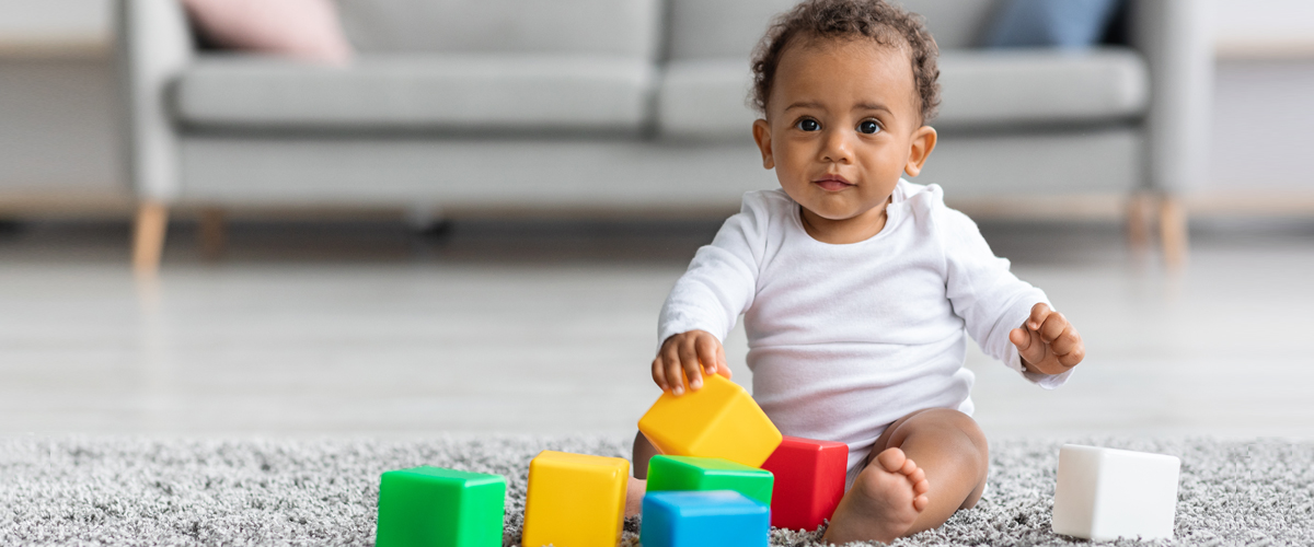 baby with blocks demonstrates updated developmental milestones