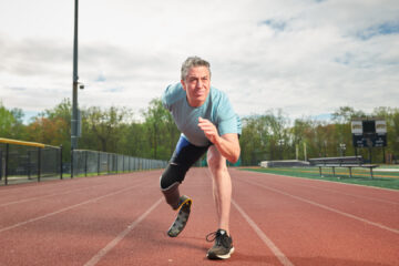 Image of Gary Yerman, who underwent a leg amputation, poised on a track preparing to run.