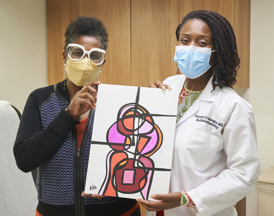 Kirtley with her radiation oncologist, Dr. Balogun, holding artwork