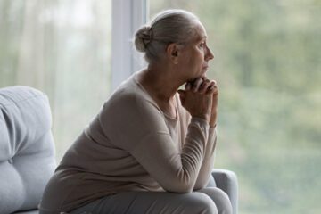 A woman looks out a window to symbolize stroke and depression.