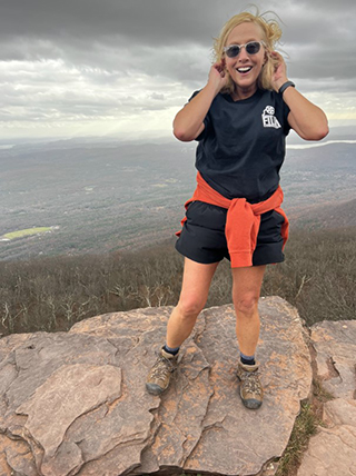 Karen standing on a rock after a hike up a mountain.