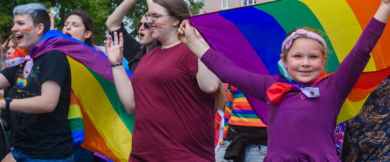 People smiling and waving rainbow flags.