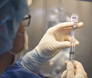 A syringe fills with lecanemab from a drug vial