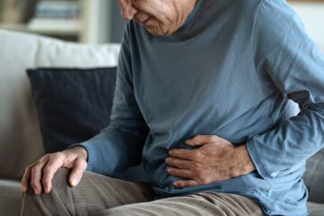Man holding stomach suffering from peptic ulcer disease