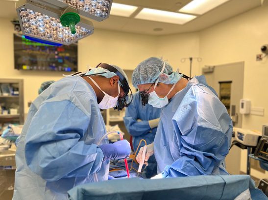 Two members of the surgical team work on Mati's heart transplant in the OR.