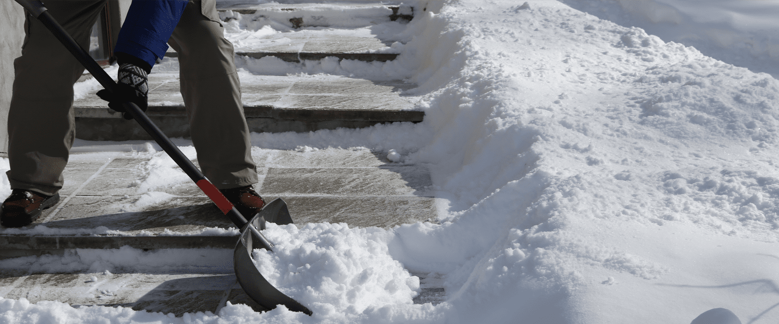 Image of a shovel moving snow on a sidewalk, to avoid back pain.