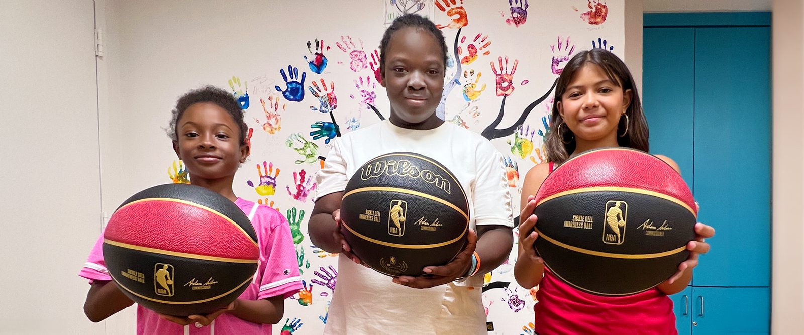 Three children hold a special-edition sickle cell ball