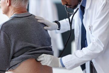 A doctor listens to a patient's lungs.