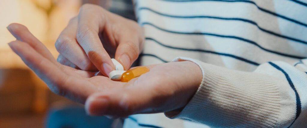 A hand holding several supplements.