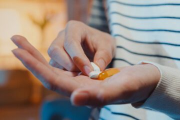 A hand holding several supplements.