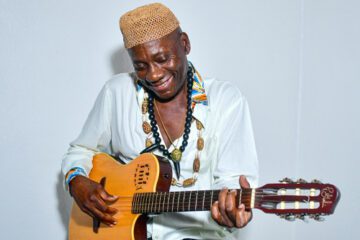 Francis Mbappe, who received a liver transplant at NewYork-Presbyterian, sitting with his bass guitar.