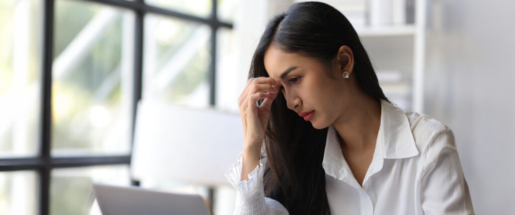 A woman touching her forehead in pain.