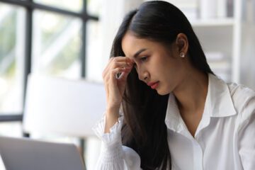A woman touching her forehead in pain.