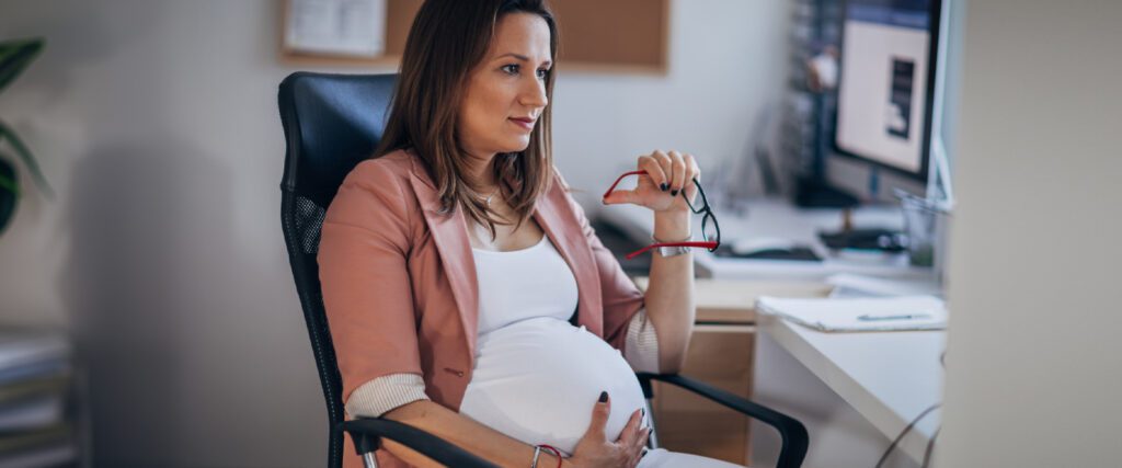 A pregnant person holding a pair of glasses
