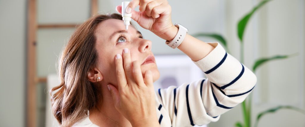 A person putting eye drops into their eye.