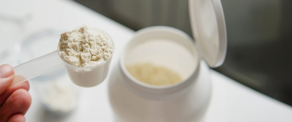 A person holding a spoon with protein powder.