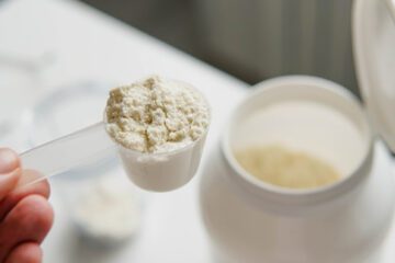 A person holding a spoon with protein powder.