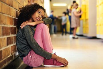 Girl in school hallway who looks sad after bullying