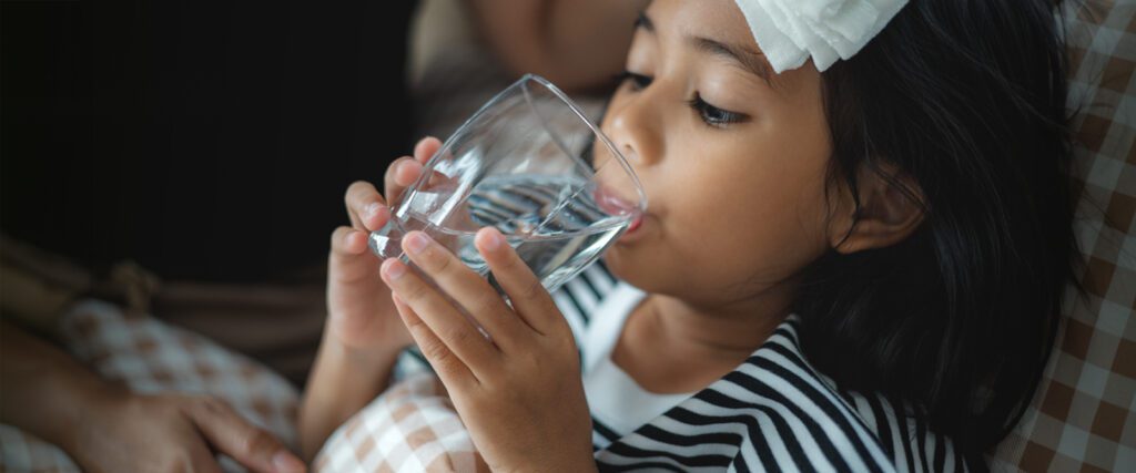 A sick child drinking a glass of water.