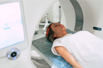 A woman lays down in a machine to get either an MRI or CT scan