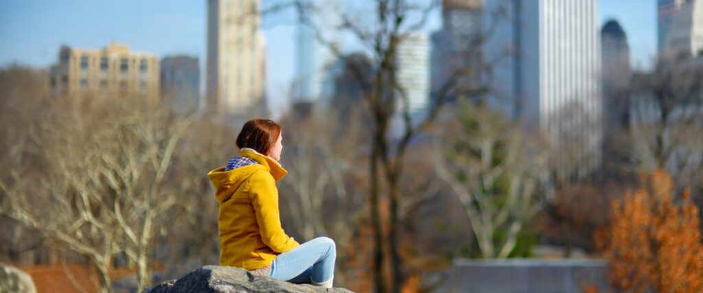 woman sitting in central park enjoying the benefits of forest bathing