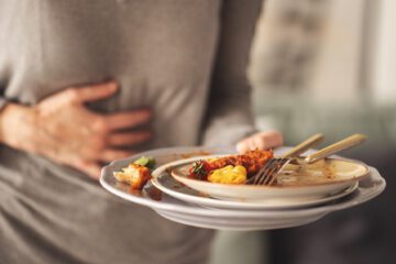 man holding plate of food with stomach ache