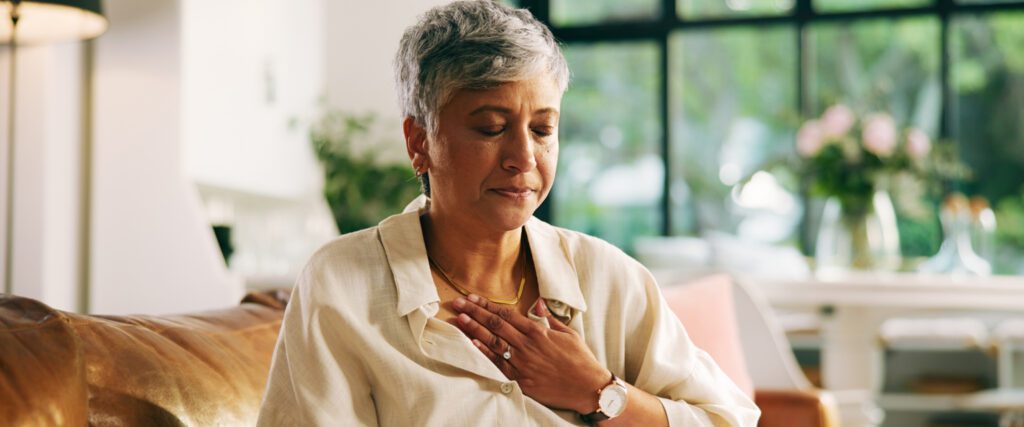 Woman at home with eyes closed and left hand resting over heart