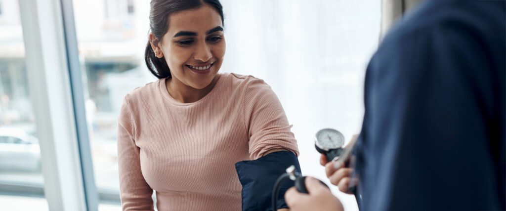 A woman having her blood pressure checked by a doctor