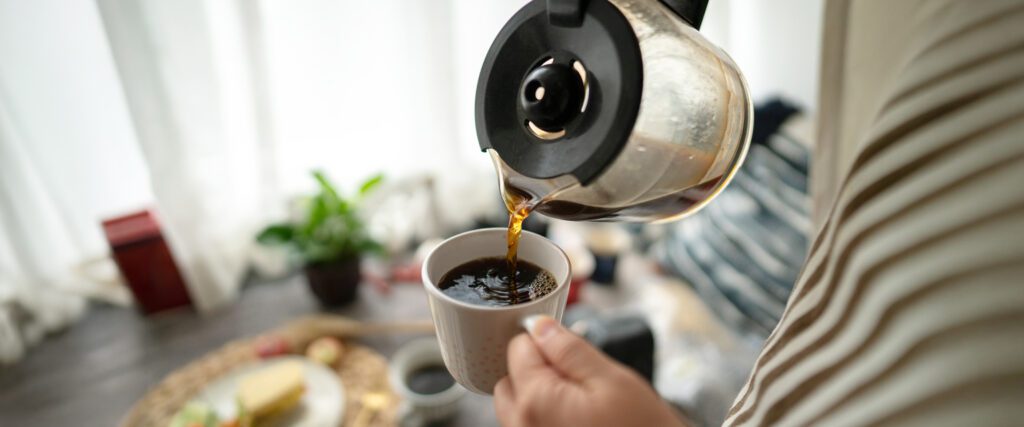 Coffee is being poured from a carafe into a coffee mug.