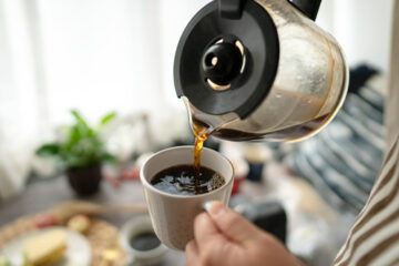 Coffee is being poured from a carafe into a coffee mug.